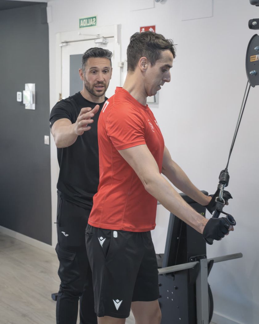 Entrenador del centro corrigiendo la técnica de un ejercicio de tracción